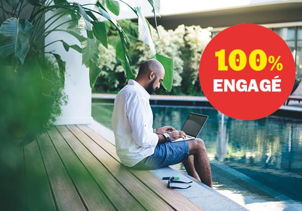 Side view of adult relaxing man sitting on poolside with feet in water while working remote on modern laptop having vacation