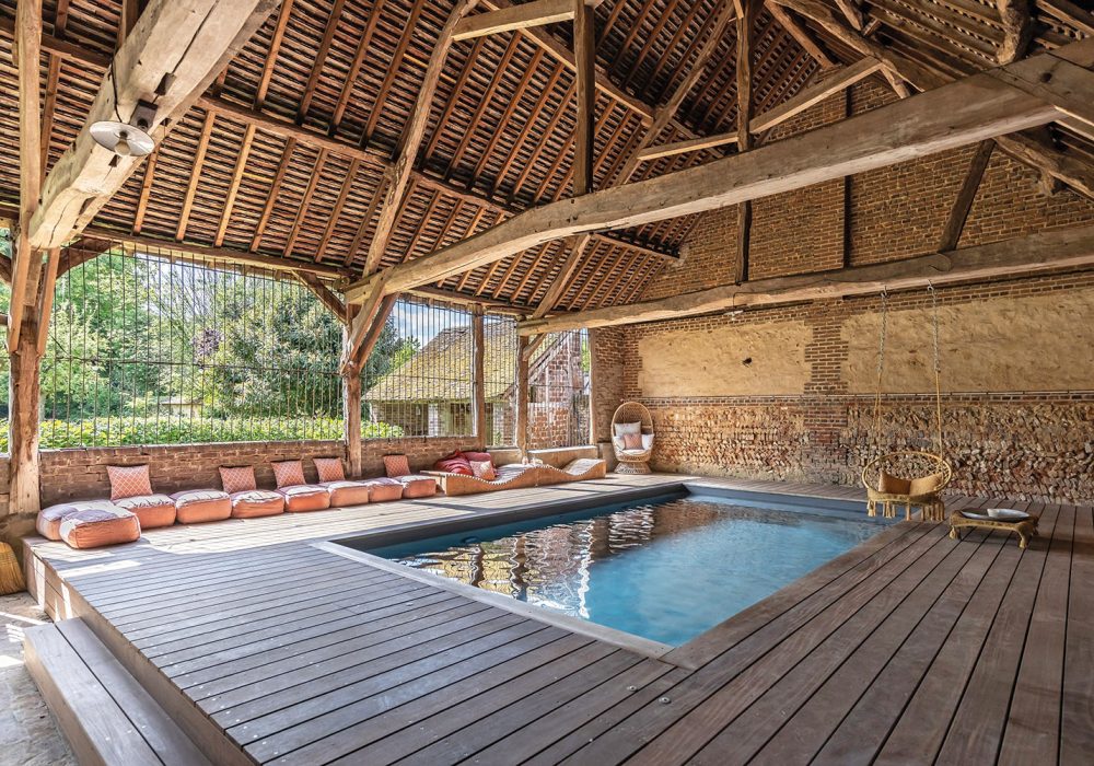 Piscine intérieure design sous la charpente d_une vieille grange déco avec liner gris 01
